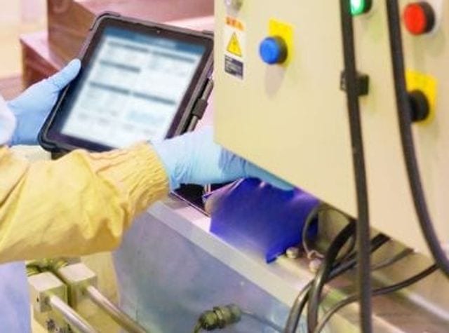 製造ラインの操作パネルとタブレットで数値を確認する様子